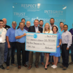group of employees smiling and holding a check for Volunteers of America from Methanex